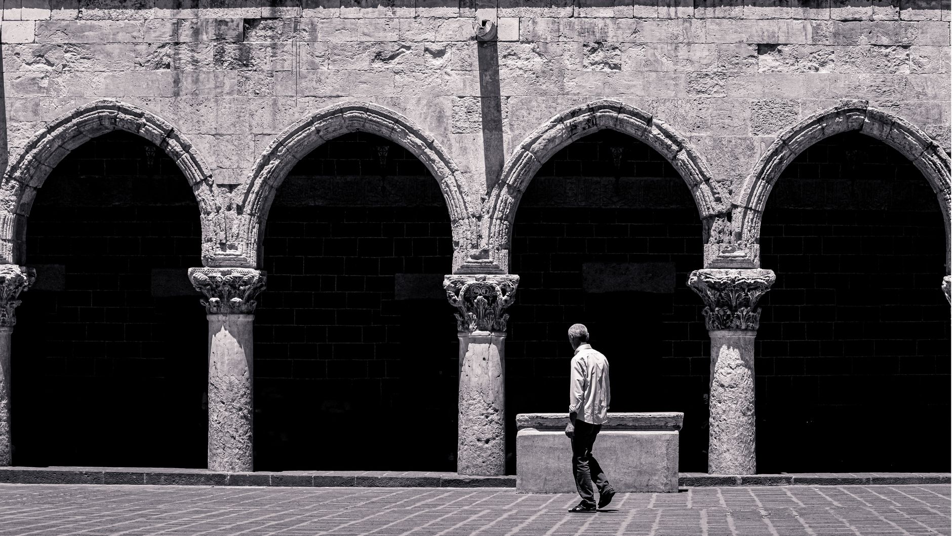man walking near sunlit colonnade